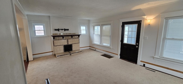 foyer entrance featuring a stone fireplace, plenty of natural light, light colored carpet, and a textured ceiling