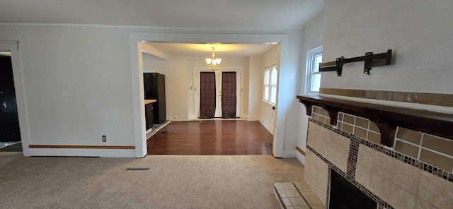 carpeted foyer entrance with ornamental molding and a notable chandelier