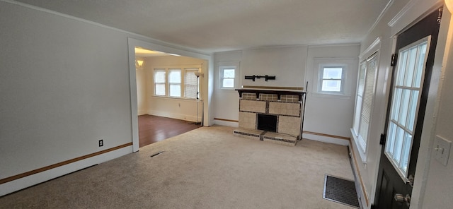 unfurnished living room featuring carpet flooring, ornamental molding, and a stone fireplace