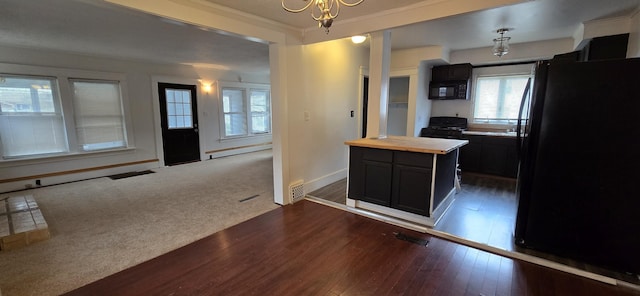 kitchen with wooden counters, a baseboard radiator, dark hardwood / wood-style flooring, a kitchen island, and black appliances