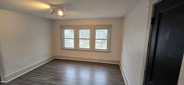 empty room with ornamental molding, dark hardwood / wood-style floors, and a textured ceiling