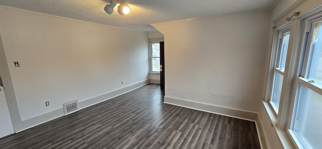 unfurnished room with dark wood-type flooring, crown molding, and a textured ceiling