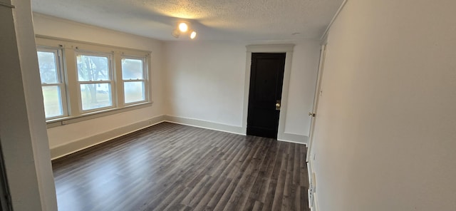 unfurnished room featuring dark wood-type flooring and a textured ceiling