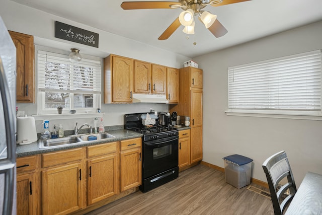 kitchen featuring black gas range oven, hardwood / wood-style floors, sink, stainless steel fridge, and ceiling fan