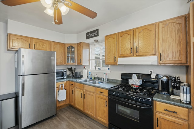 kitchen featuring dark hardwood / wood-style floors, stainless steel refrigerator, sink, ceiling fan, and black gas stove