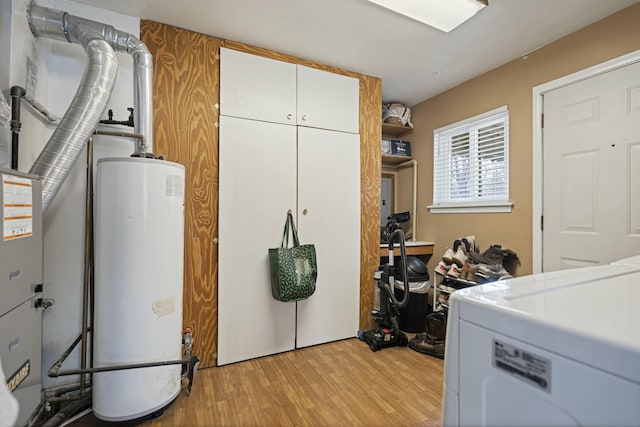 laundry room featuring cabinets, water heater, and light hardwood / wood-style flooring