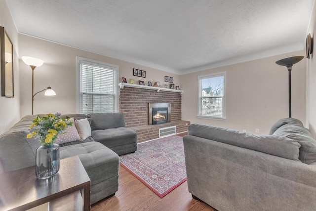 living room featuring hardwood / wood-style flooring, a fireplace, and a textured ceiling