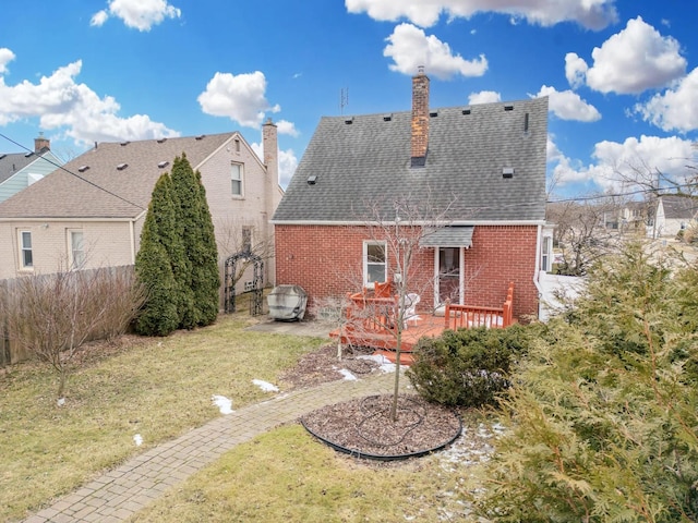 rear view of house with a wooden deck and a lawn