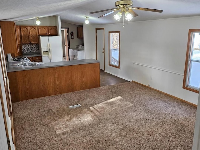 2054 Woodside Dr, Caro, MI 48723 - kitchen featuring white fridge with ice dispenser, washer and dryer, dark carpet, brown cabinetry, and plenty of natural light
