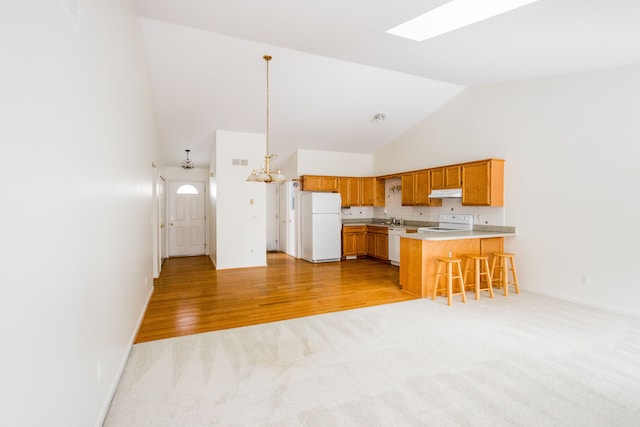 kitchen with decorative light fixtures, light carpet, a kitchen breakfast bar, kitchen peninsula, and white appliances