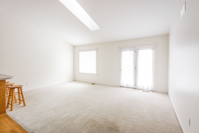 carpeted empty room featuring lofted ceiling with skylight