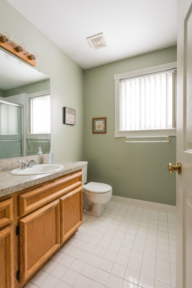 bathroom featuring tile patterned flooring, vanity, a shower with door, and toilet