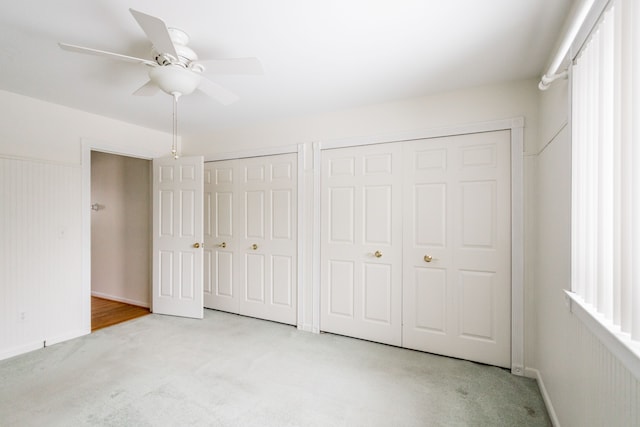 unfurnished bedroom with light carpet, two closets, and ceiling fan