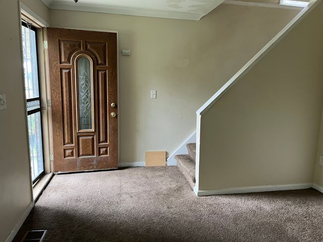 carpeted entrance foyer with ornamental molding