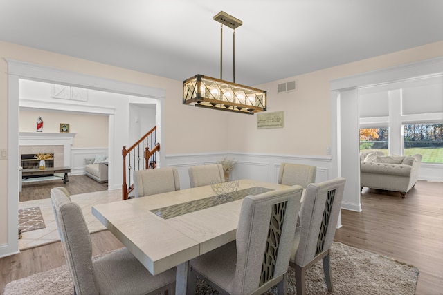 dining area with a tile fireplace and light wood-type flooring