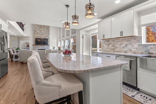 kitchen with a breakfast bar, white cabinetry, stainless steel appliances, a kitchen island, and decorative light fixtures