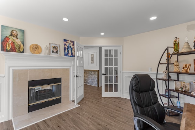 home office featuring french doors, hardwood / wood-style floors, and a tile fireplace