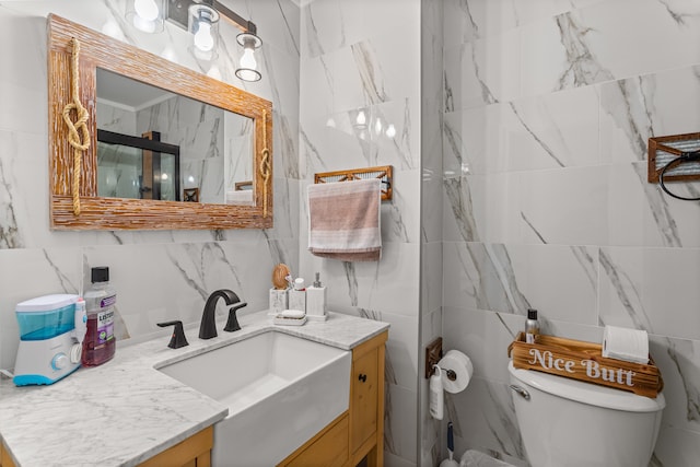 bathroom featuring vanity, toilet, and tile walls