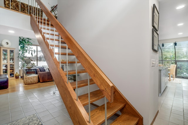 staircase with a high ceiling, a healthy amount of sunlight, and tile patterned floors