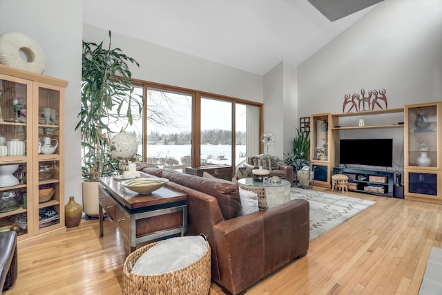 living room featuring high vaulted ceiling and light wood-type flooring