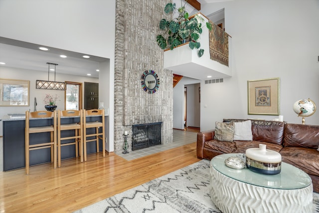 living room featuring hardwood / wood-style flooring, a tiled fireplace, and a high ceiling