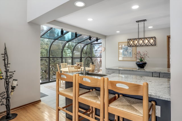 dining room featuring sink, light wood-type flooring, and a wall of windows