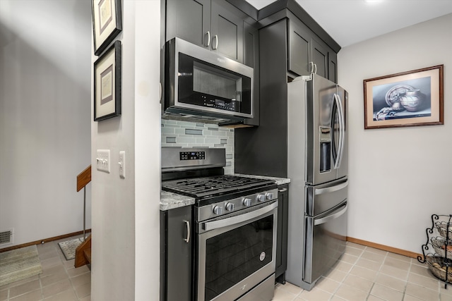 kitchen with stainless steel appliances, light stone countertops, light tile patterned floors, and backsplash