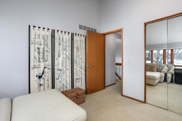 carpeted bedroom featuring a towering ceiling and a closet