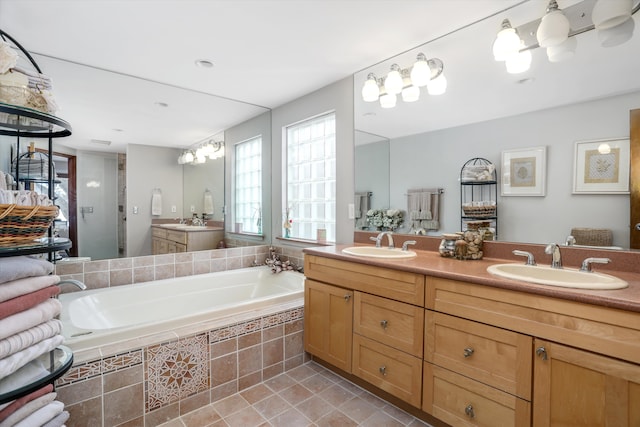 bathroom featuring vanity, a relaxing tiled tub, and tile patterned floors