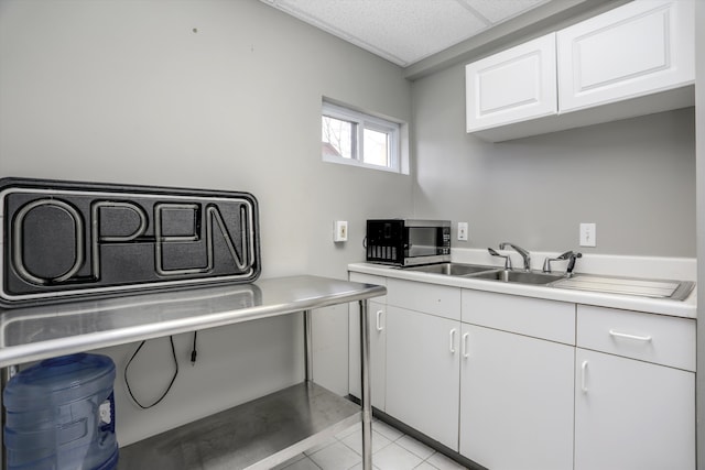 kitchen featuring light tile patterned floors, sink, and white cabinets