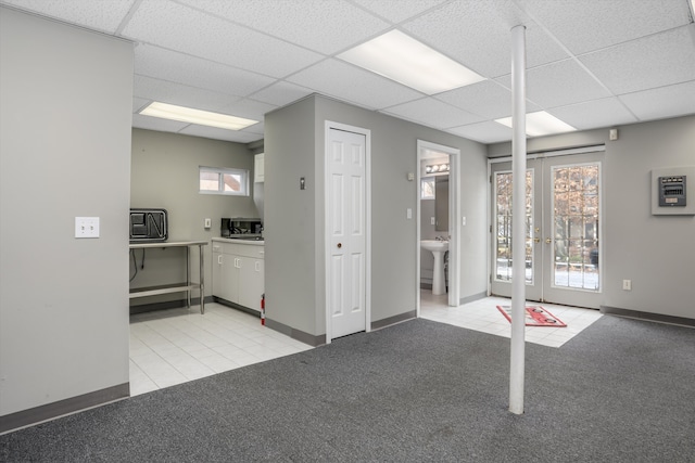 interior space featuring french doors, sink, light carpet, and a drop ceiling