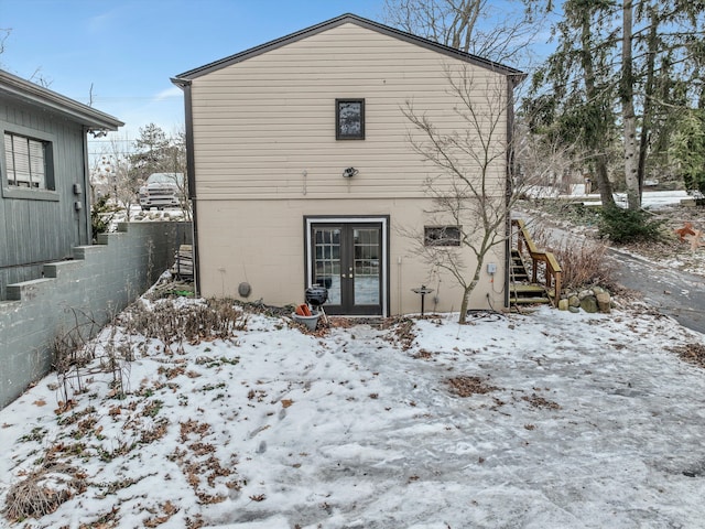 snow covered rear of property featuring french doors