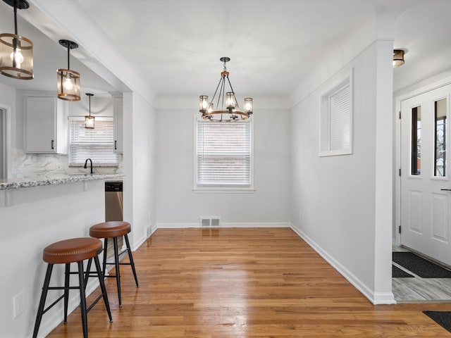 dining area featuring sink, a notable chandelier, and light wood-type flooring