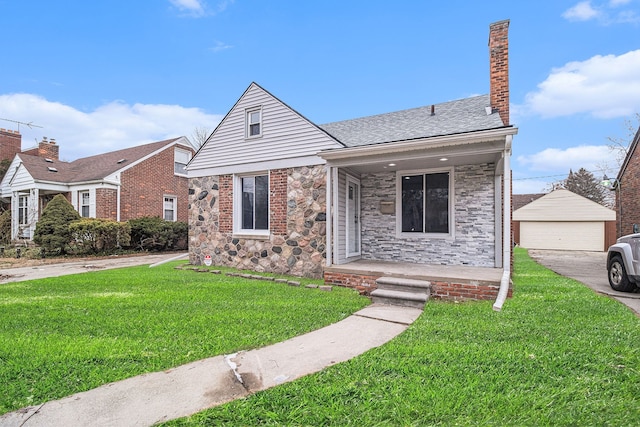 view of front facade featuring a porch, a garage, an outbuilding, and a front lawn