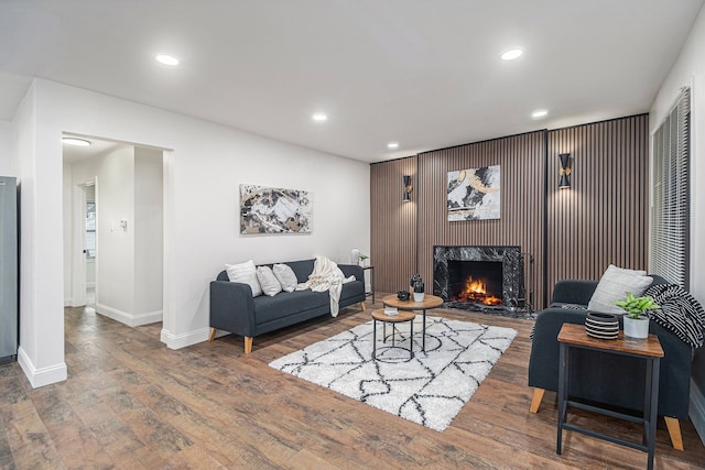 living room featuring a high end fireplace and dark wood-type flooring