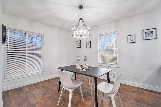 dining space with dark wood-type flooring and a chandelier