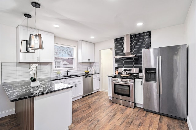 kitchen with wall chimney exhaust hood, sink, hanging light fixtures, appliances with stainless steel finishes, and white cabinets