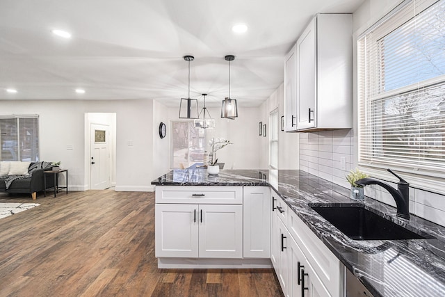 kitchen with sink, white cabinetry, dark hardwood / wood-style floors, decorative light fixtures, and dark stone counters