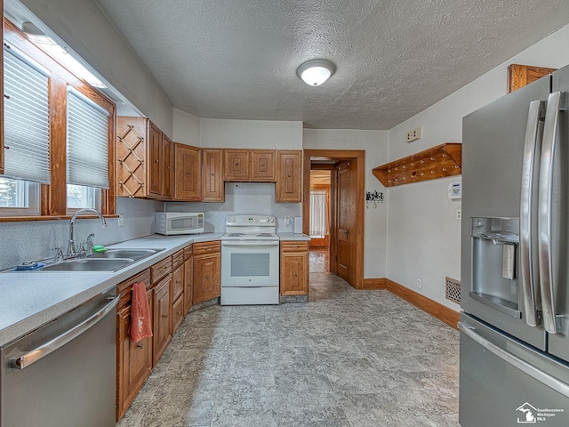 kitchen with appliances with stainless steel finishes, sink, and a textured ceiling