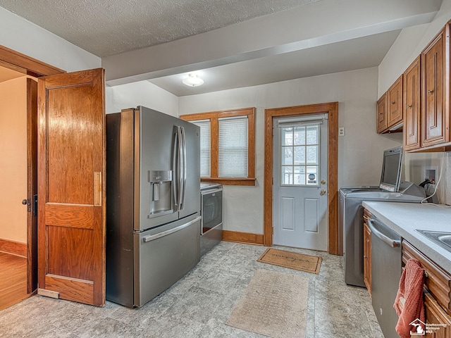 kitchen with washing machine and clothes dryer, stainless steel appliances, and a textured ceiling