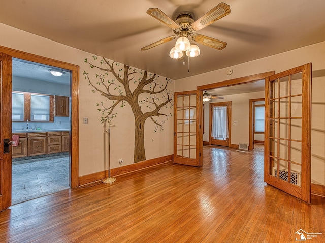 unfurnished room featuring sink, french doors, ceiling fan, and light wood-type flooring