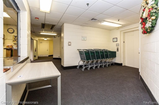 interior space featuring visible vents, a paneled ceiling, and concrete block wall