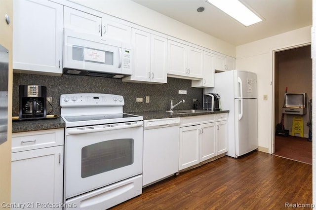 kitchen featuring white appliances, dark countertops, tasteful backsplash, and a sink