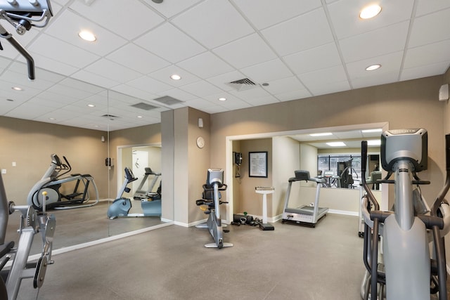 workout area with a paneled ceiling, visible vents, and baseboards