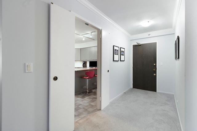 carpeted entrance foyer with crown molding and rail lighting