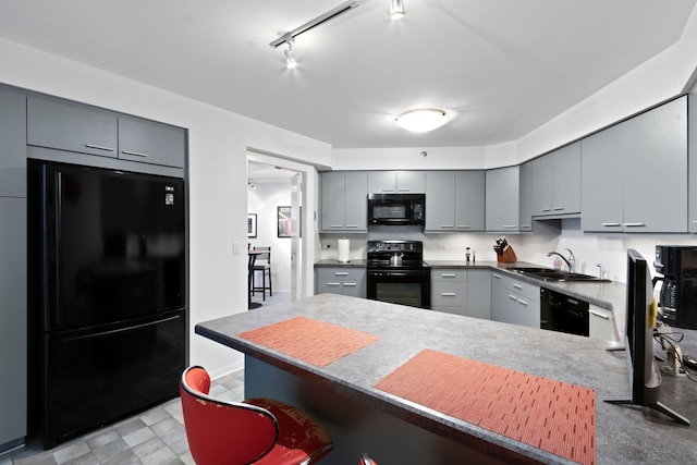 kitchen featuring sink, gray cabinets, kitchen peninsula, decorative backsplash, and black appliances