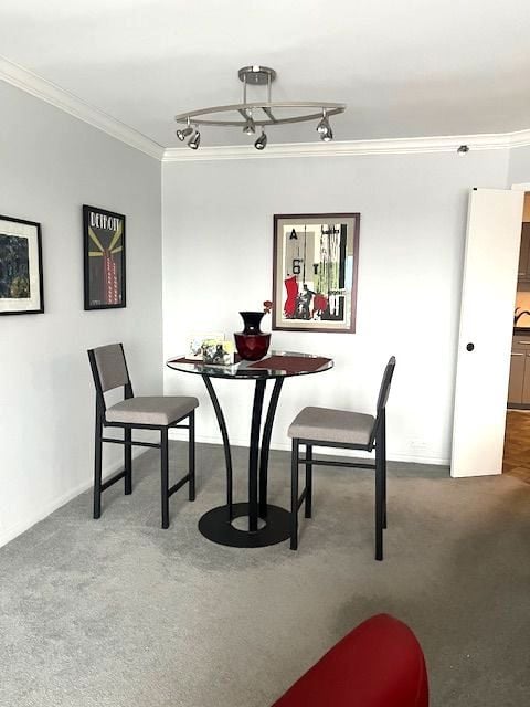 dining room with track lighting, carpet flooring, and crown molding