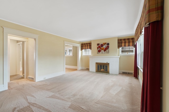 unfurnished living room with crown molding, light colored carpet, and a brick fireplace