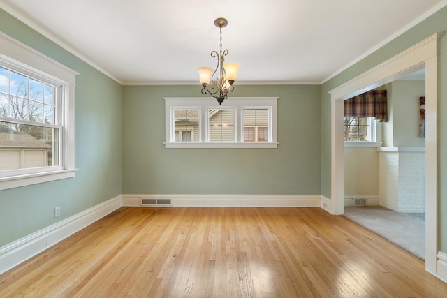 unfurnished dining area featuring an inviting chandelier, ornamental molding, and light wood-type flooring