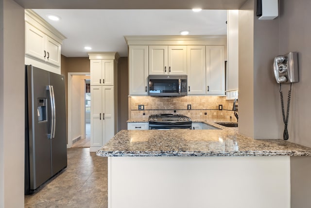 kitchen with light stone counters, sink, kitchen peninsula, and appliances with stainless steel finishes